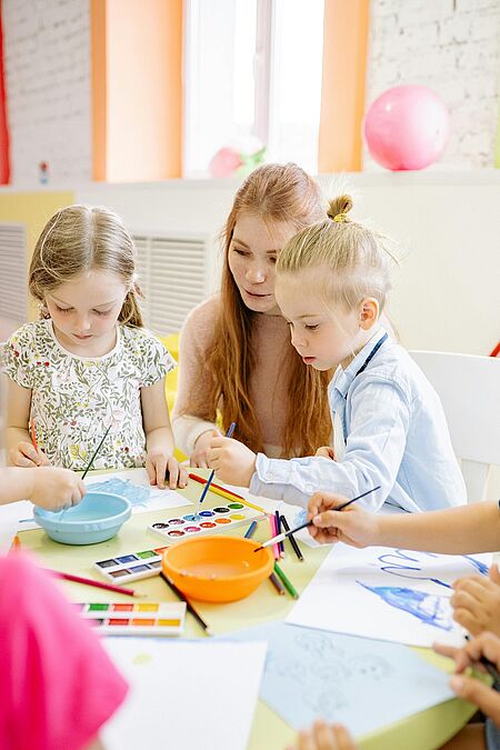 Aquarellkurs für die ganze Familie Eine Frau und zwei Kinder malen mit Aquarellfarben.